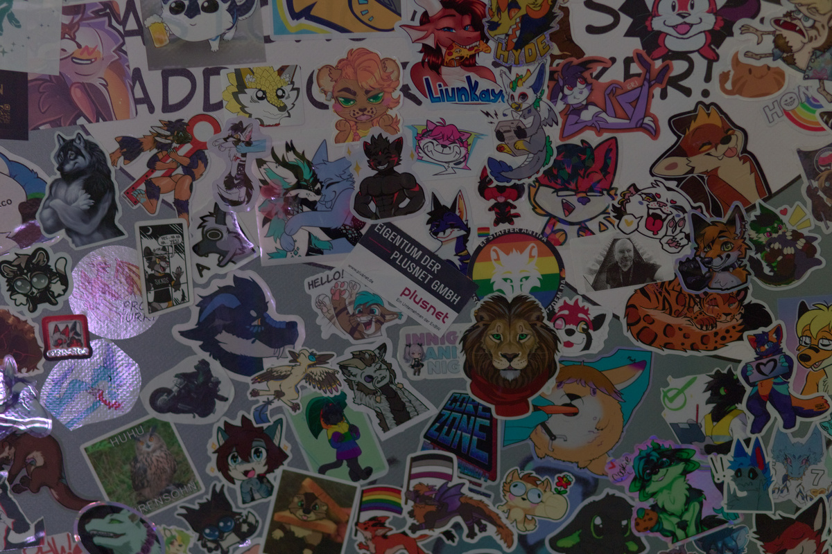 Sticker wall: in the middle is a 'Eigentum der Plusnet GmbH' inventory sticker surrounded by a lot of other furry stickers